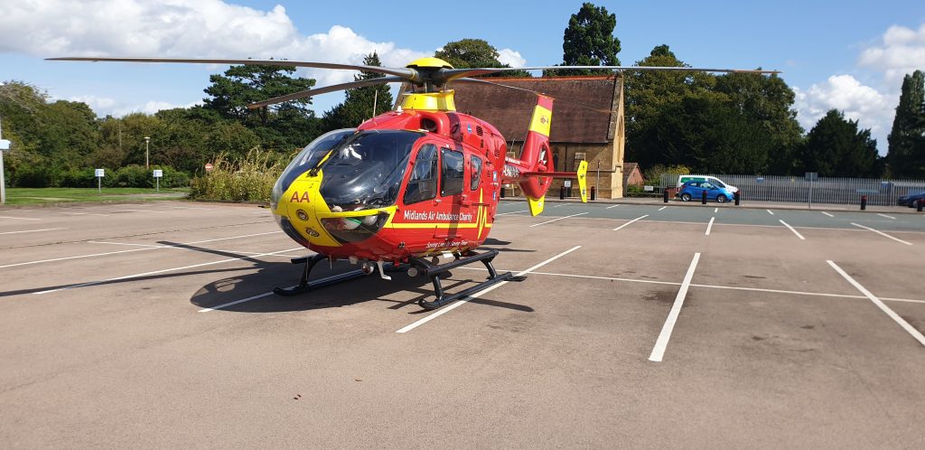 Red EC135 helicopter in a car park